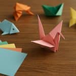 Colorful origami paper cranes and animals arranged on a table, showcasing creative folding designs