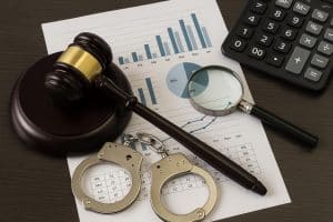 White collar crime investigation concept with documents, handcuffs, and financial charts