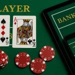 Stack of casino chips and baccarat cards on a green table symbolizing online baccarat strategy