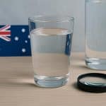 Close-up of a clear glass filled with tap water next to a kitchen faucet in an Australian home