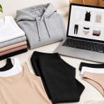 Stack of folded women’s basic clothing in neutral colors on a clean, minimal background